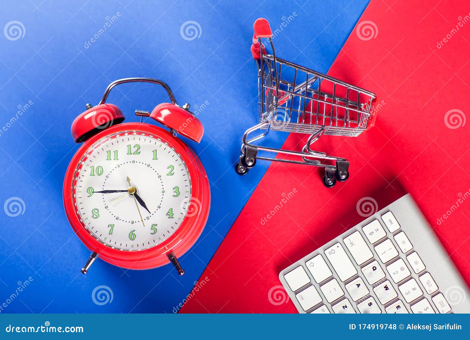 alarm clock, shopping trolley and keyboard on the doubble color background. online shopping and sales concept