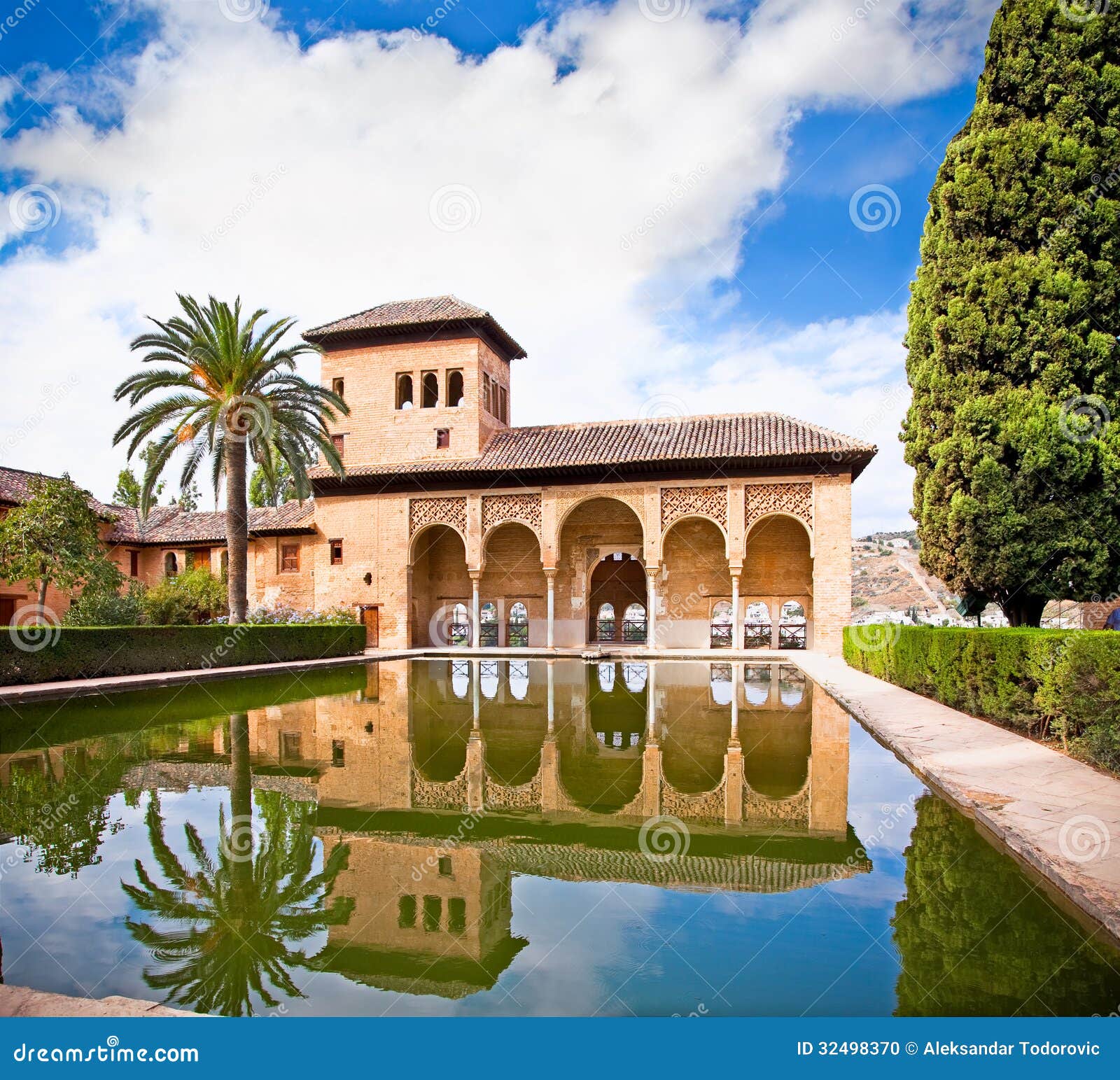 alhambra palace reflected in water in granada. spain.