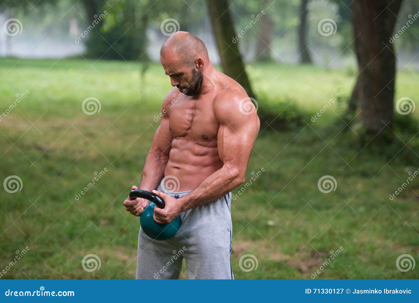 Allenamento dell'uomo di esercizio dell'oscillazione di Kettlebell di forma fisica all'aperto. Esercizio maschio di giovane forma fisica con il bollitore Bell - l'oscillazione di Kettlebell