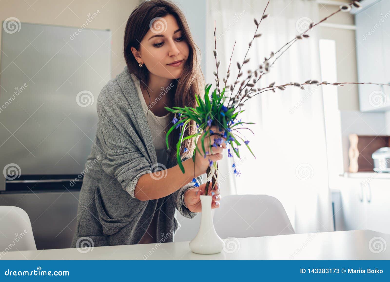 allergy free. happy woman putting spring flowers in vase on kitchen. seasonal allergy concept