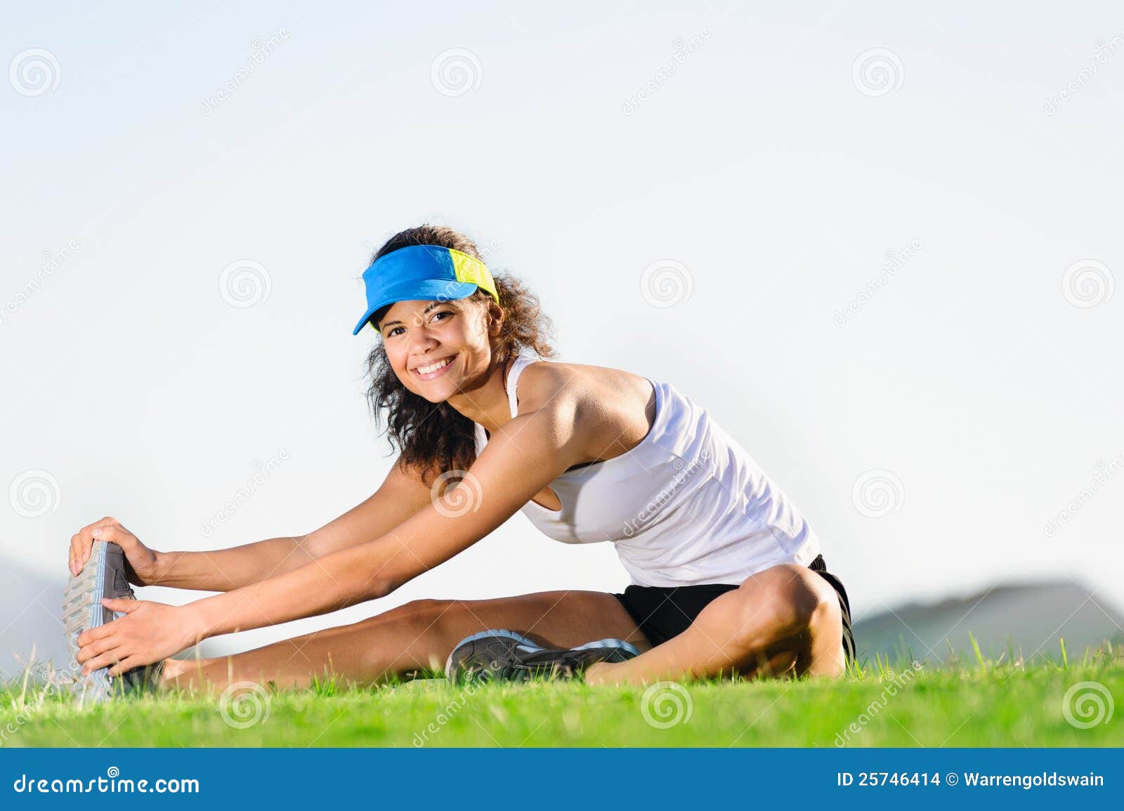 Allungamento dell'atleta. Atleta che allunga il muscolo del piedino all'aperto mentre sedendosi sull'erba. stile di vita sano felice di un corridore di maratona