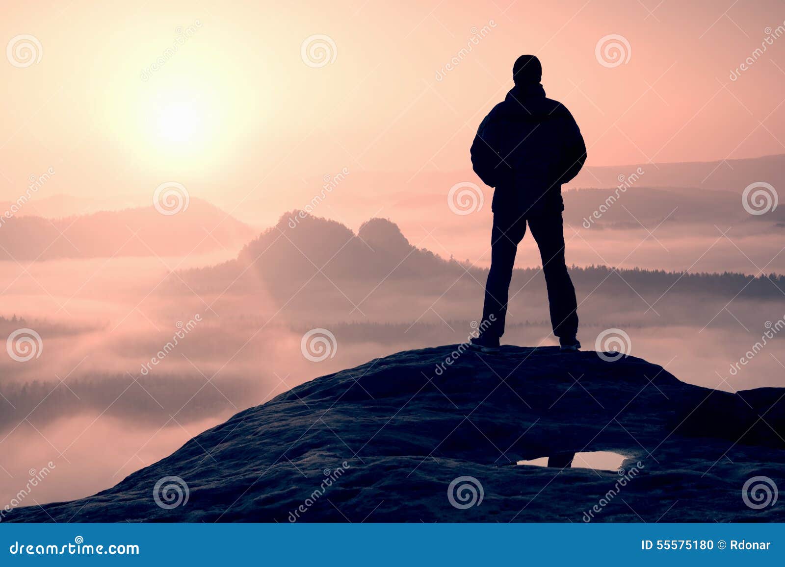 Alone Hiker Standing on Top of a Mountain and Enjoying Sunrise Stock