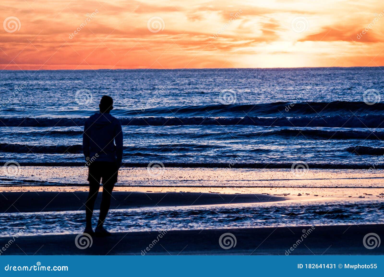 alone man silueta looking at the sea at dusk but blue and red sky in the background