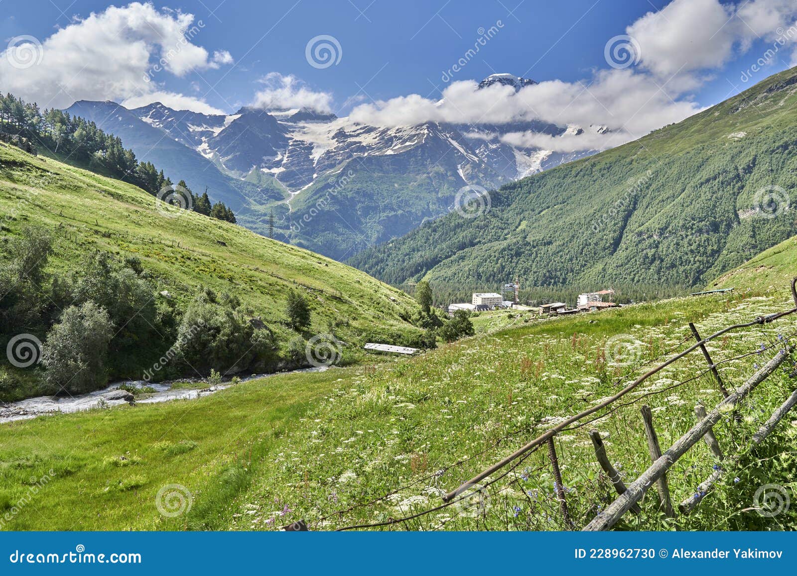 Alpine Green Meadows In The Mountains And Snow Capped Peaks Stock Photo