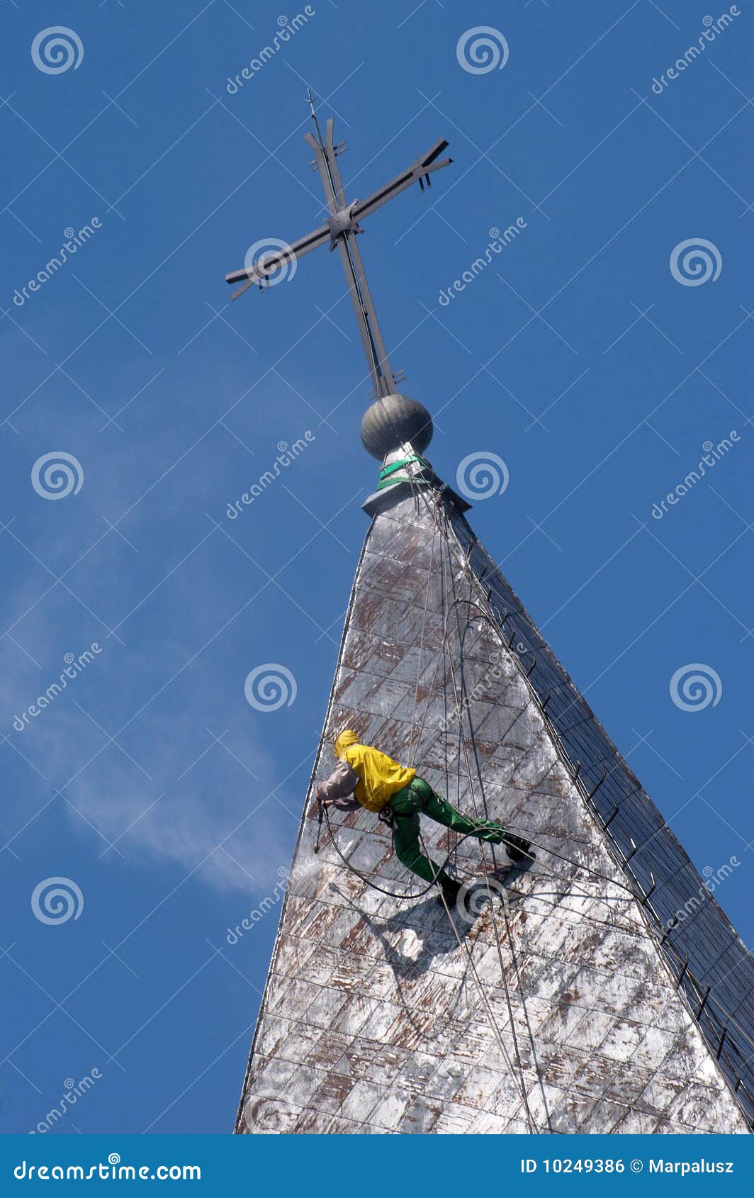 Alpinist cleans church roof. Climber on a dome of the church, carrying out works under pressure washing a roof