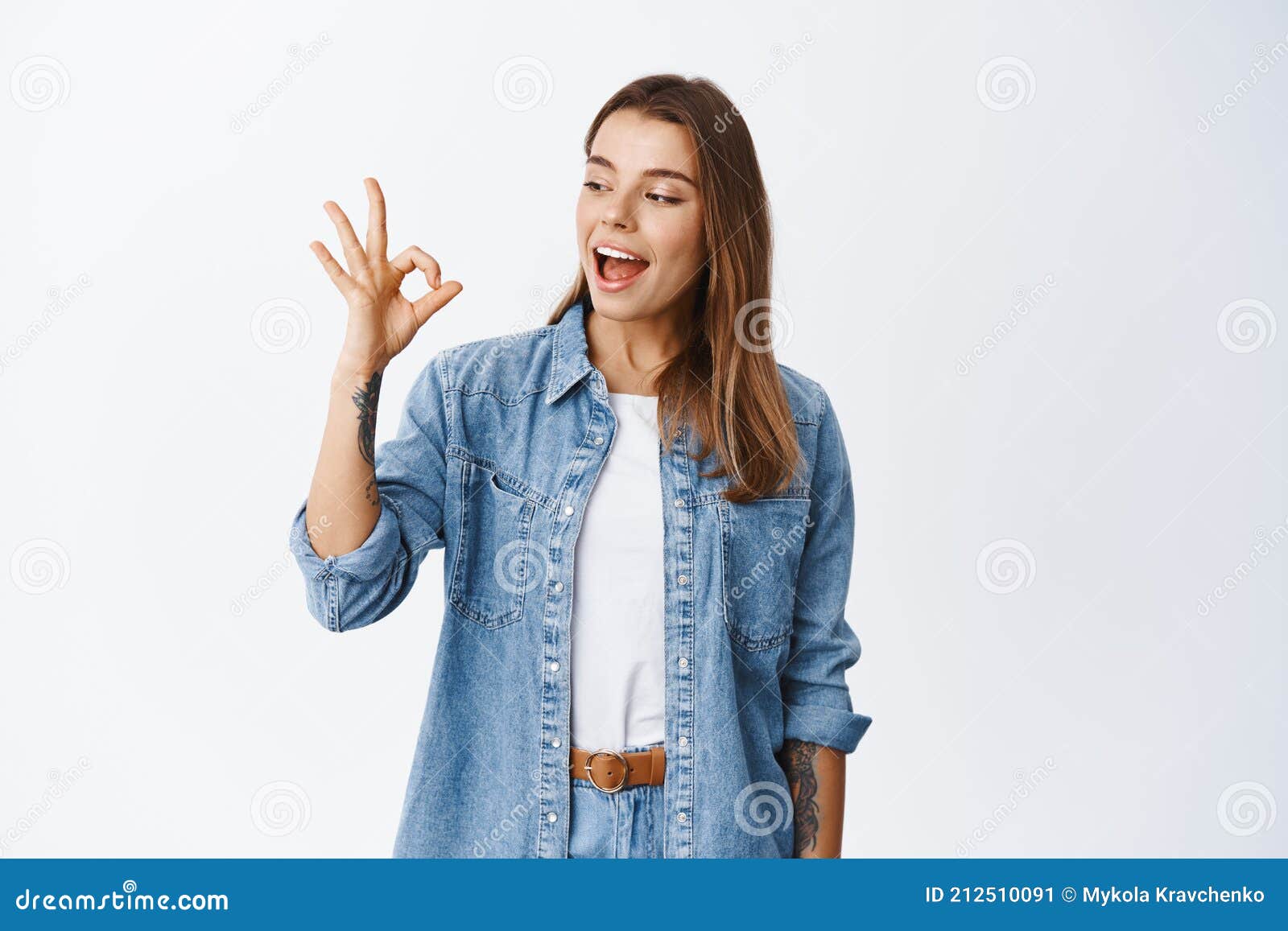 alright. smiling cute girl showing okay sign and say yes, approve something good, like and agree, standing pleased