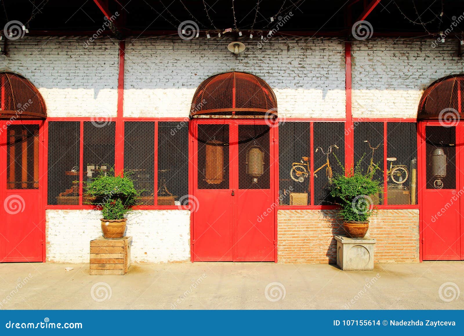 Alte Backsteinmauer mit roten Türen und Fenster und zwei Blumentöpfe Bangkok, Thailand