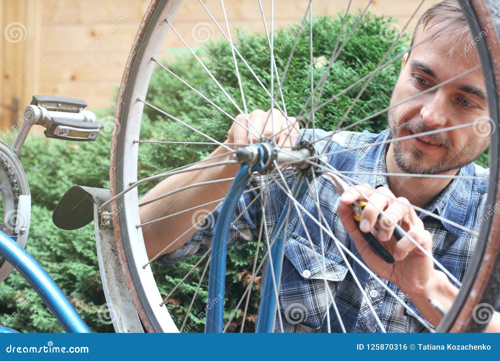 Altes Weinlesefahrrad der jungen bärtigen Mannreparatur im Freien