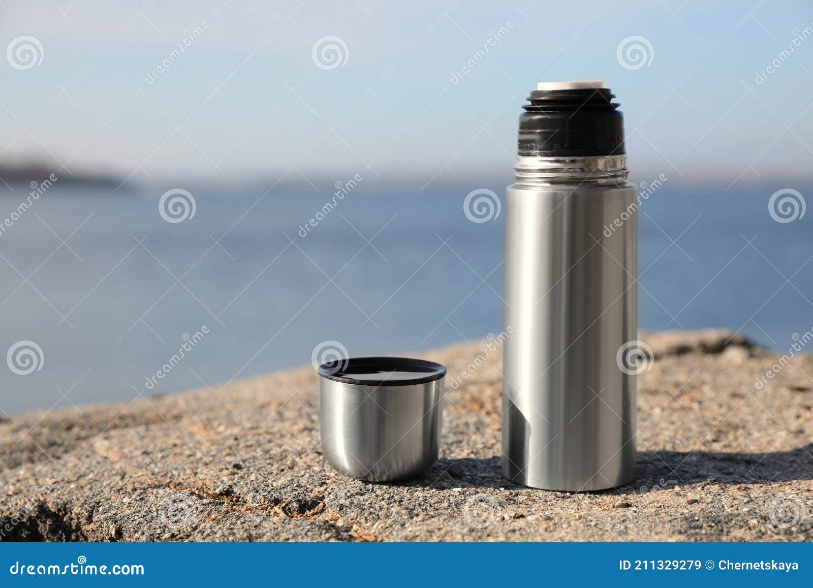 Aluminium Thermos with Hot Drink on Rock Stone Outdoors. Space for