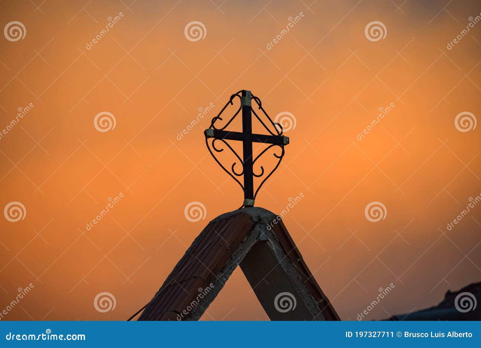 minimalism . the first lights of the day, orange sky and a religious cross in the forefront , in a nw desert region of argentina
