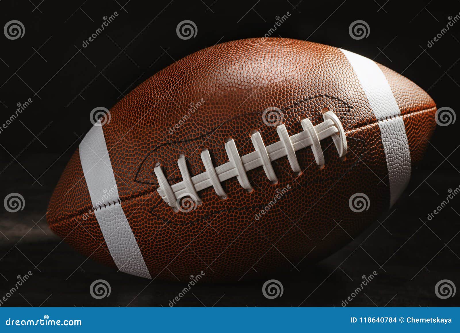 American Football Ball on Table Against Dark Background Stock Photo