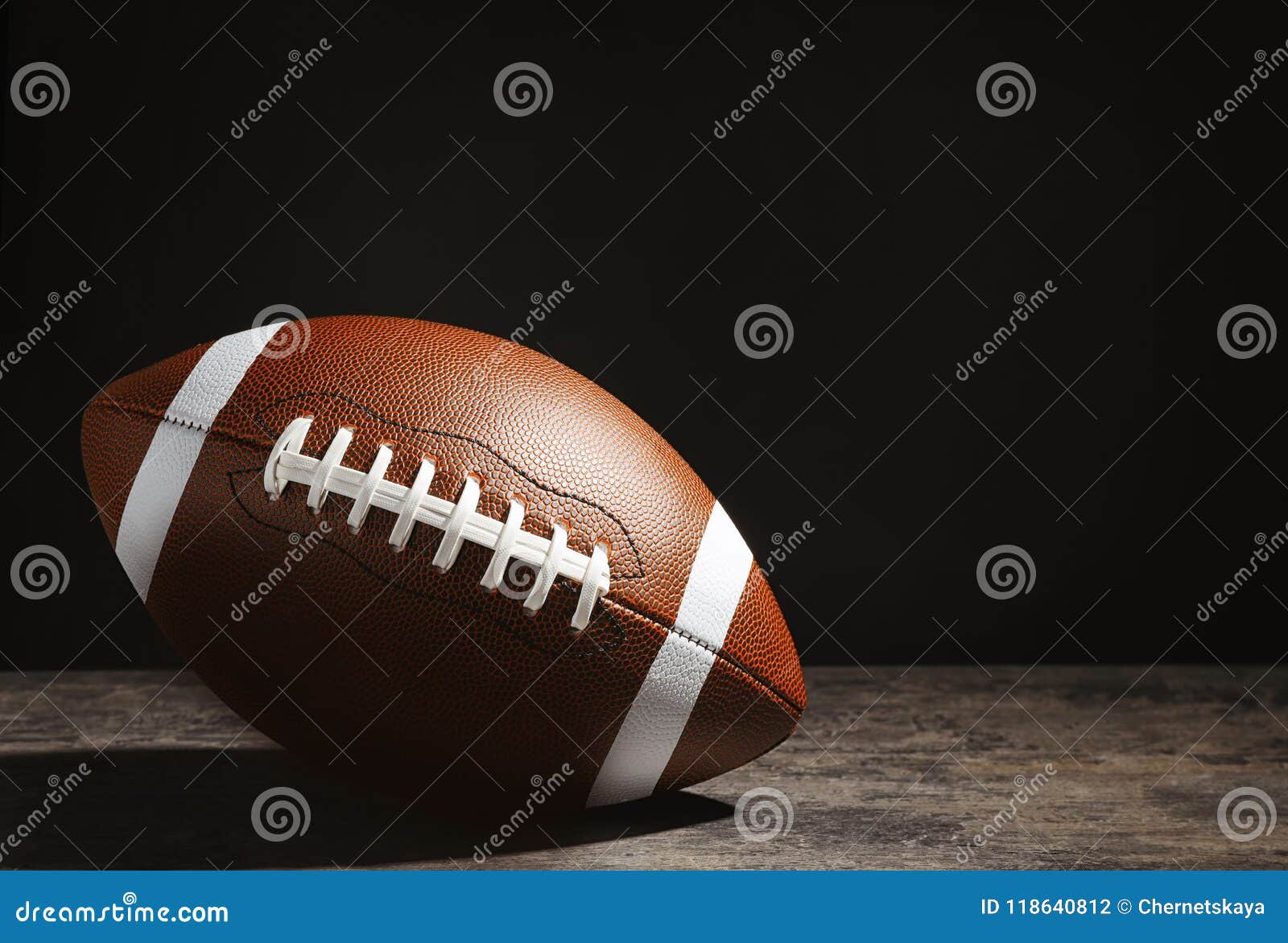 American Football Ball on Table Against Dark Background Stock Photo
