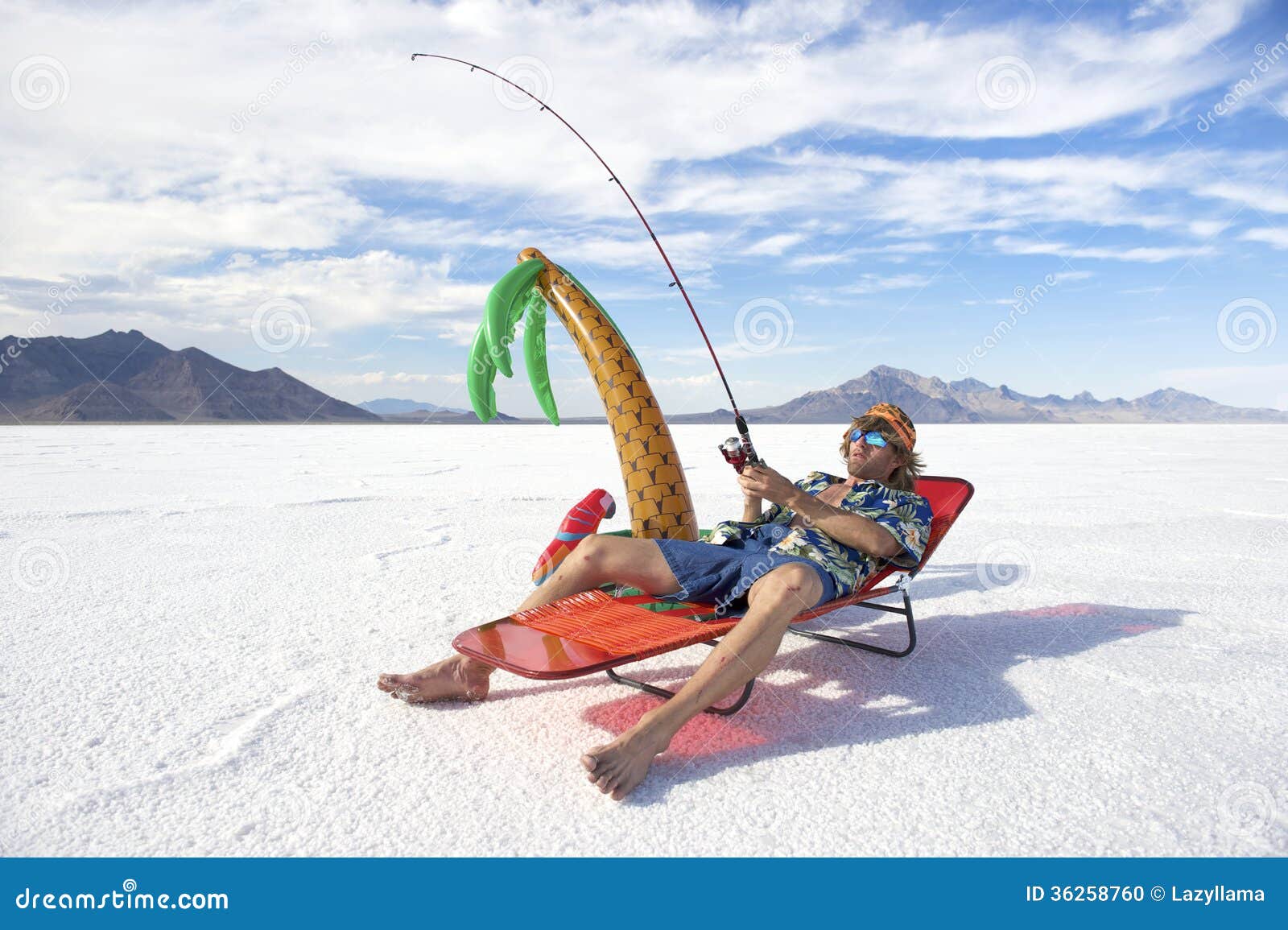 Amerykański rybak Iść na Tanim Lodowym połowu wakacje wakacje. Wsioka Amerykański rybak jest ubranym Hawajską koszula iść na tanim lodowym połowu wakacje wakacje z nadmuchiwanym drzewkiem palmowym w biel pustyni