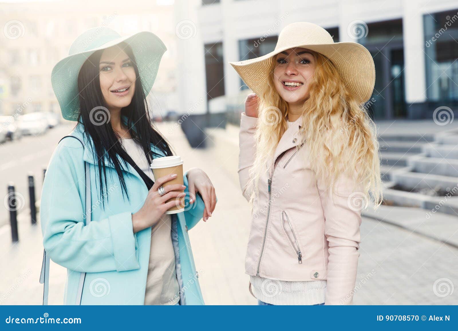 Amies dans des chapeaux avec du café. Amies dans des chapeaux et avec du café sur la rue au printemps