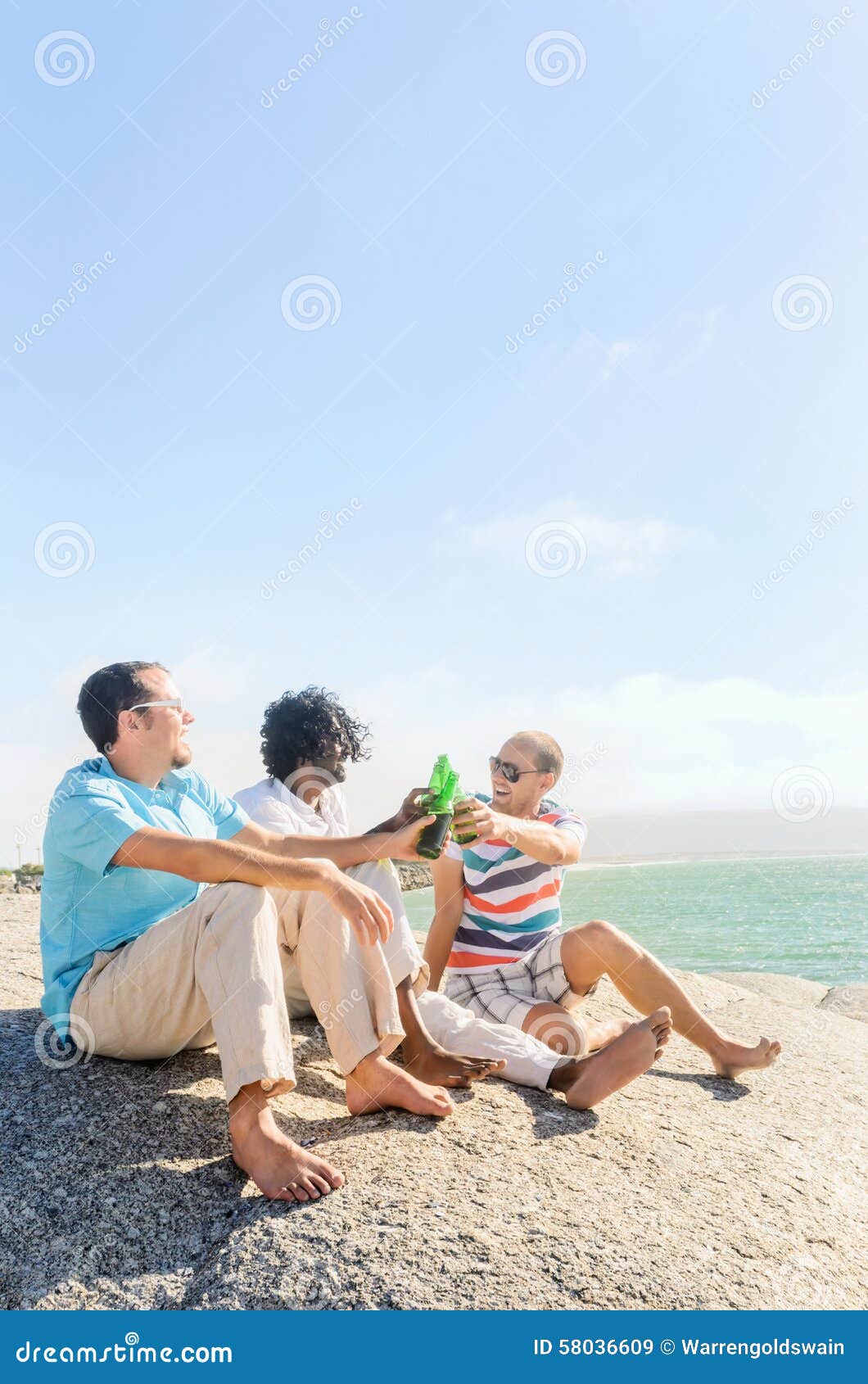 Amigos que relaxam com certas cervejas. Amigos que penduram para fora pelas cervejas bebendo da praia, apreciando a tarde ensolarada