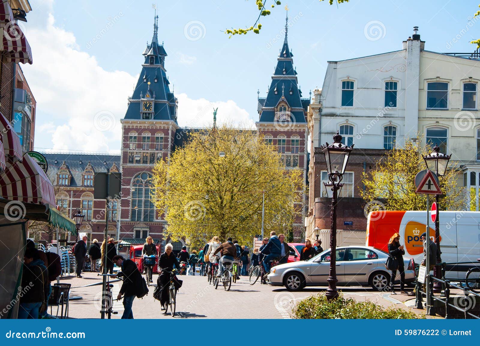 AMSTERDAM-APRIL 30 ：当地人民在阿姆斯特丹街道骑自行车， Rijksmuseum是可看见的在背景中. AMSTERDAM-APRIL 30 ：当地人民在阿姆斯特丹街道骑自行车， Rijksmuseum是可看见的在2015年4月30日，荷兰的背景中