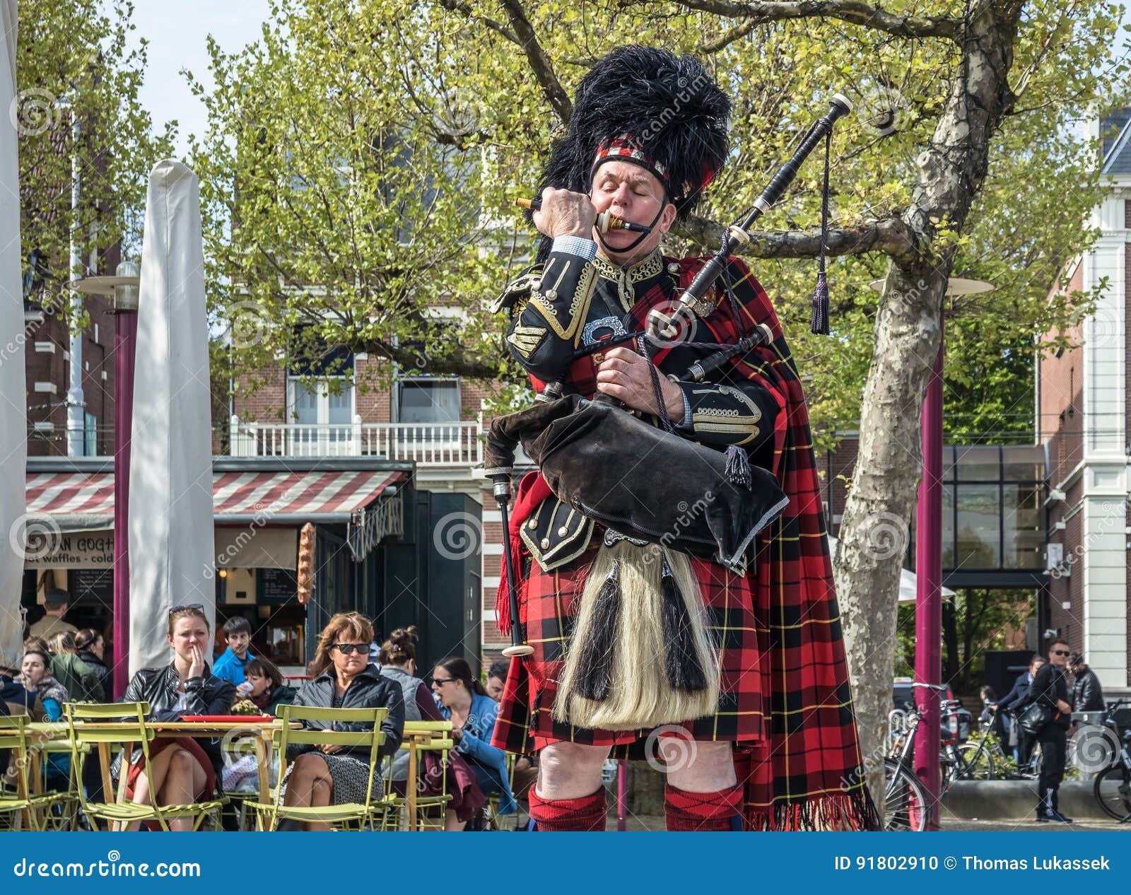 Amsterdam, die Niederlande - 31. April 2017: Schottischer Dudelsackspieler, der sein Instrument in den Straßen von Amsterdam-Trag. AMSTERDAM, DIE NIEDERLANDE - 31. APRIL 2017: Schottischer Dudelsackspieler, der sein Instrument in den Straßen von Amsterdam seinen königlichen Stuart-Schottenstoffkilt und -Plaid tragend abstimmt