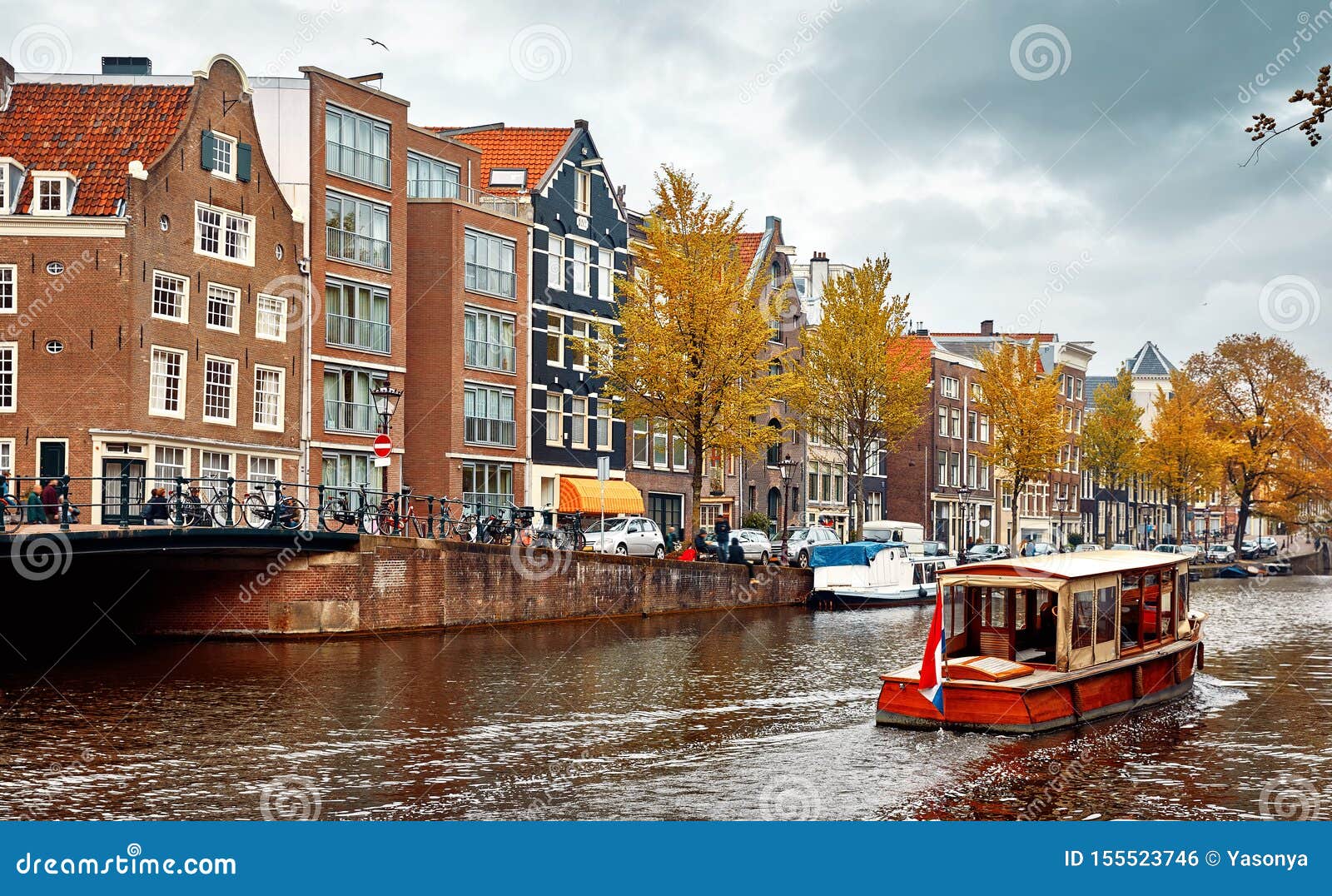 Amsterdam Nederl?nderna Husb?tar som dansar hus. Amsterdam, Netherlands. Floating Houses and houseboats and boats at channels by banks. Traditional dutch dancing houses among trees. Evening autumn street above water pink sunset sky with clouds.