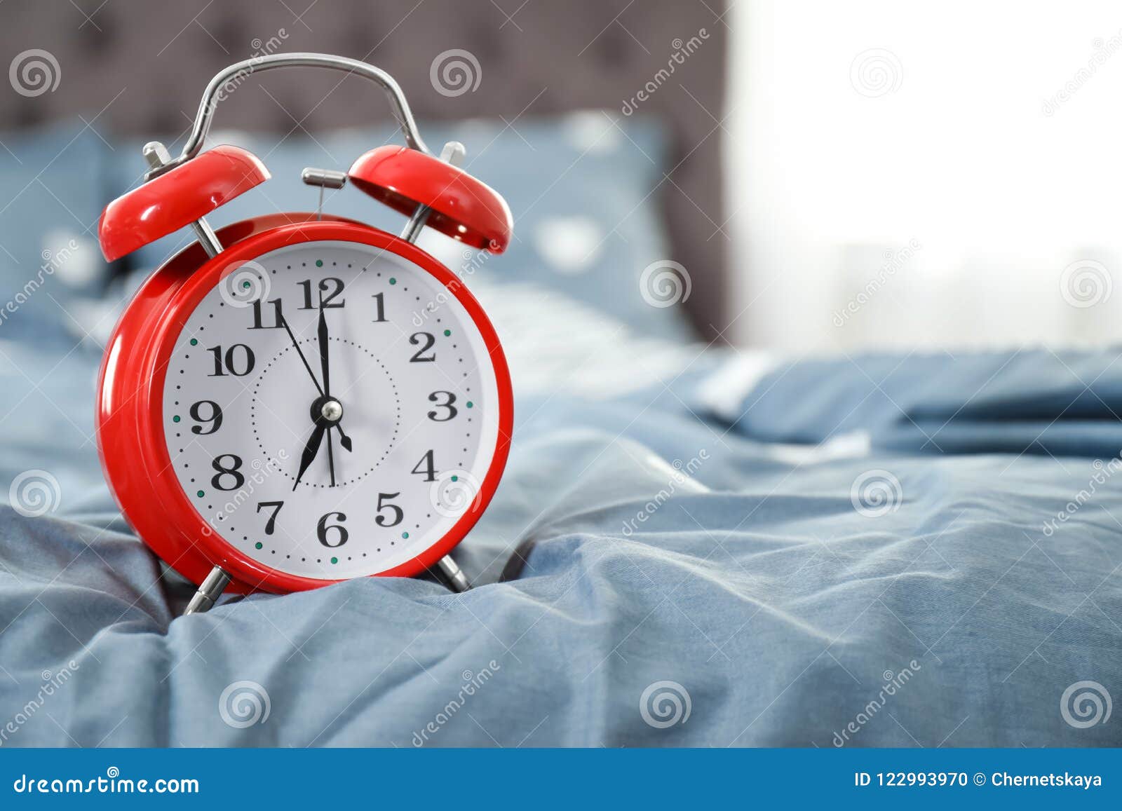 Analog alarm clock on bed. stock photo. Image of clock 122993970
