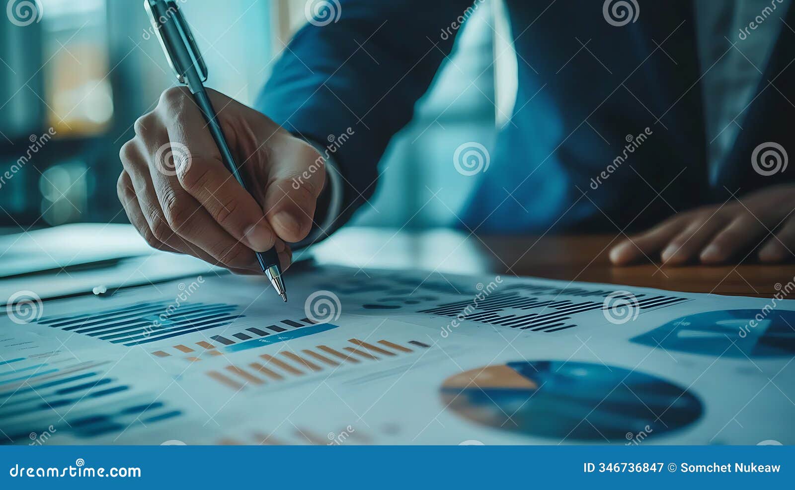 analyzing business performance a hand holding a pen over financial data charts for strategic decisions and growth insights