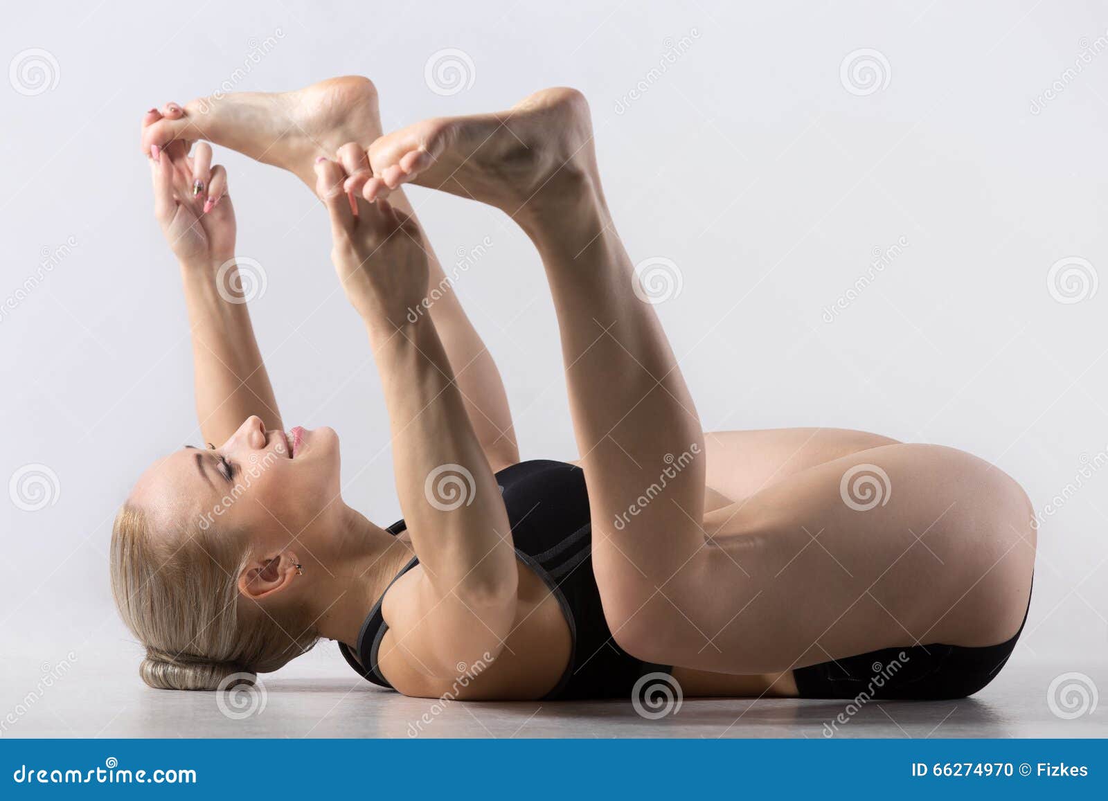 practicing yoga, stretching in Ananda Balasana exercise, Happy Baby pose,  working out, wearing black sportswear, cool urban style, full length, grey  studio background, side view. happy baby pose Stock Photo | Adobe