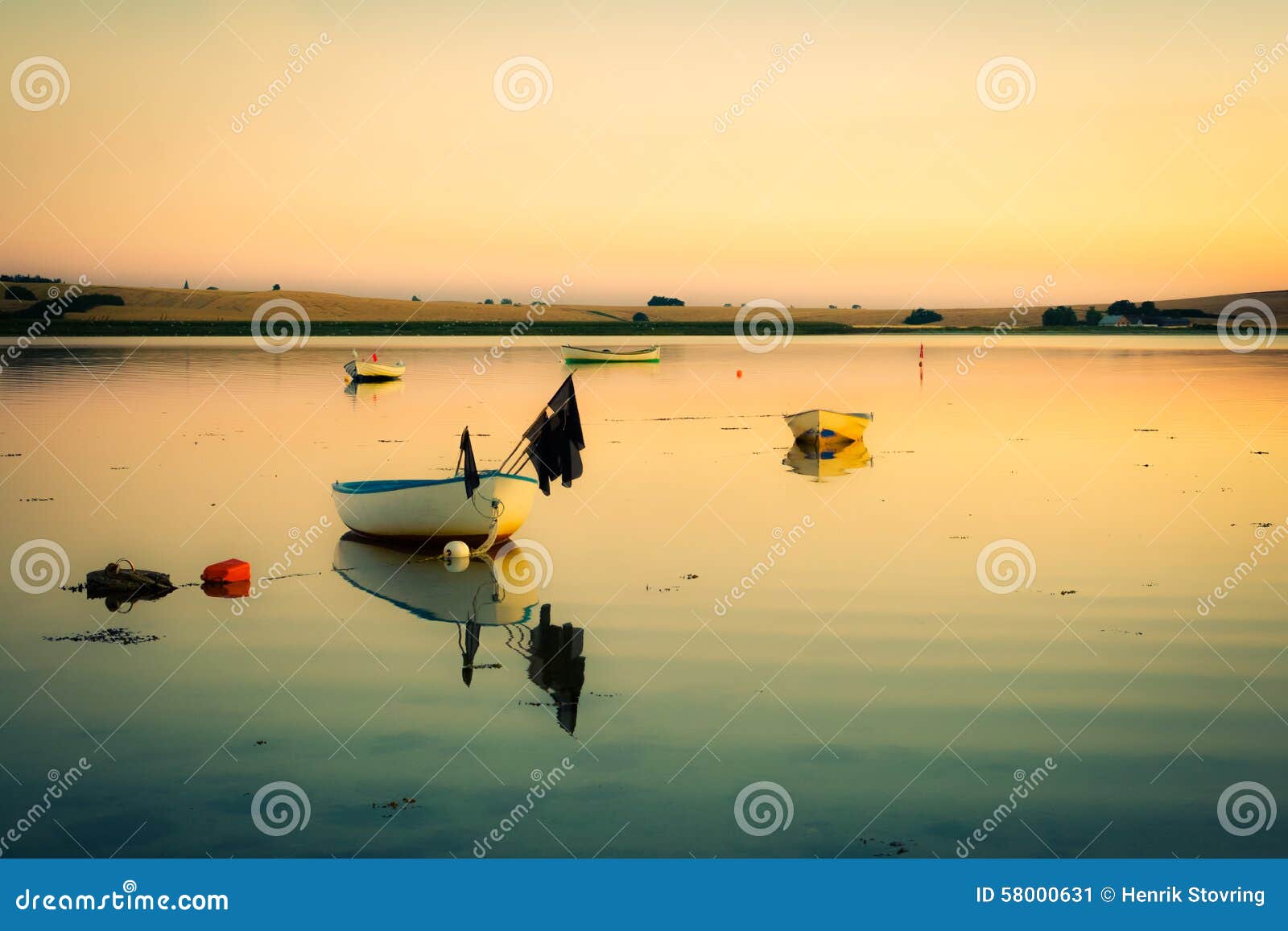 Anche calma alla baia (retro). Le piccole barche si trovano in una piccola baia al tramonto sull'acqua calma con le ondulazioni molli - pacifiche e idilliache
