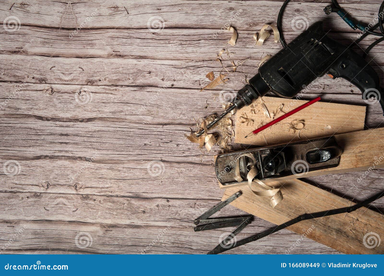 Outil de travail d'un charpentier Ancienne menuiserie en métal, plieuse, perceuse électrique, crayon, planches et rasages sur fond de bois Espace libre pour votre texte