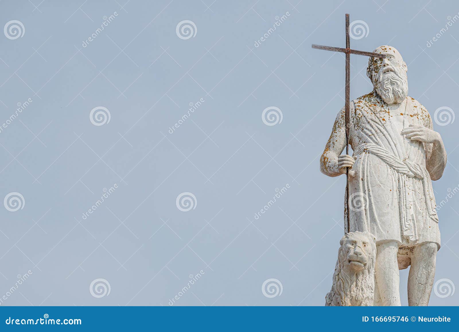 ancient aged sculpture of poor stranger pilgrim with cross and sitting lion at roof of santa maria assunta jesuits church in