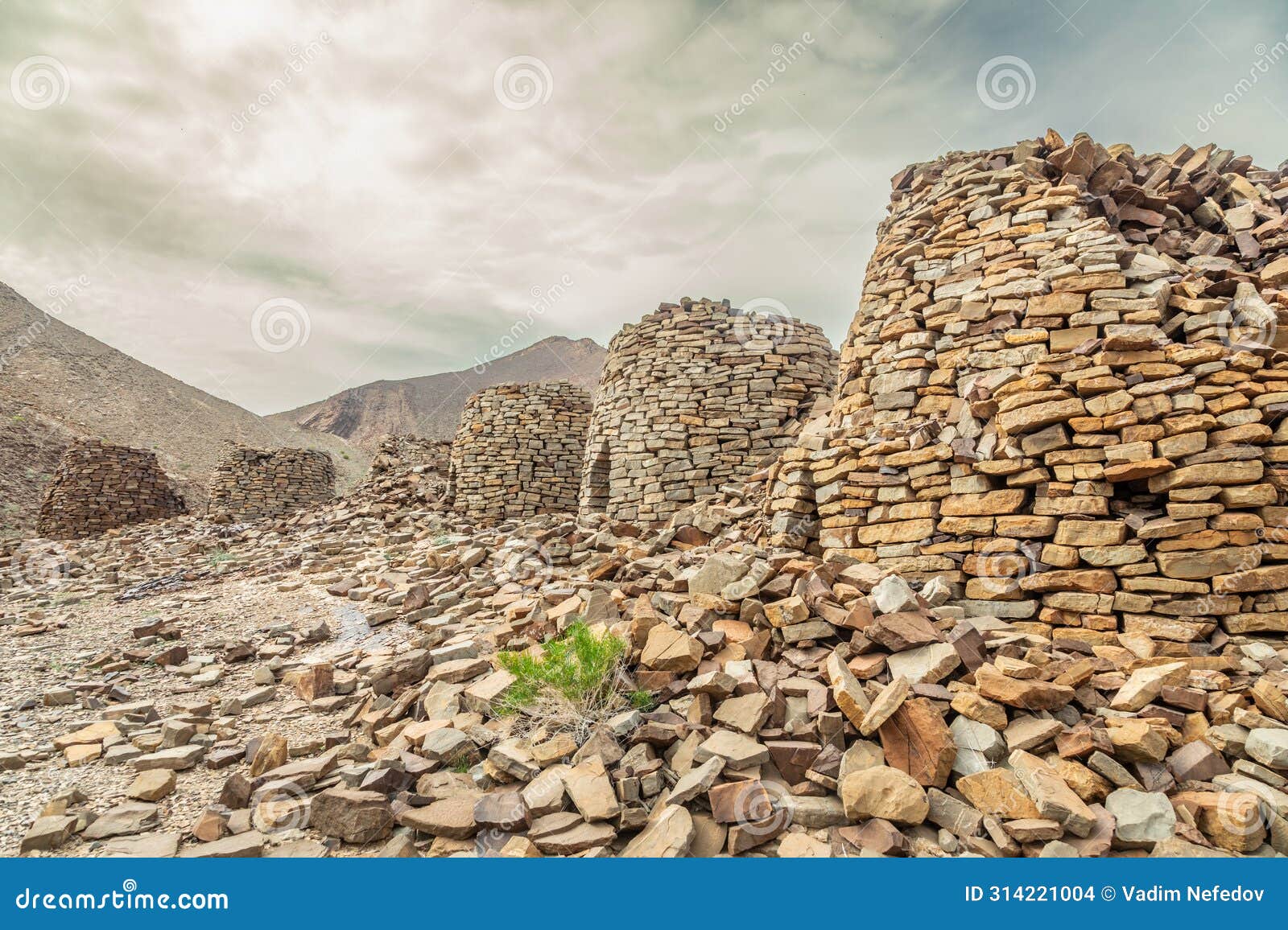 ancient stone beehive tombs with jebel misht mountain in the background, archaeological site near al-ayn, sultanate oman