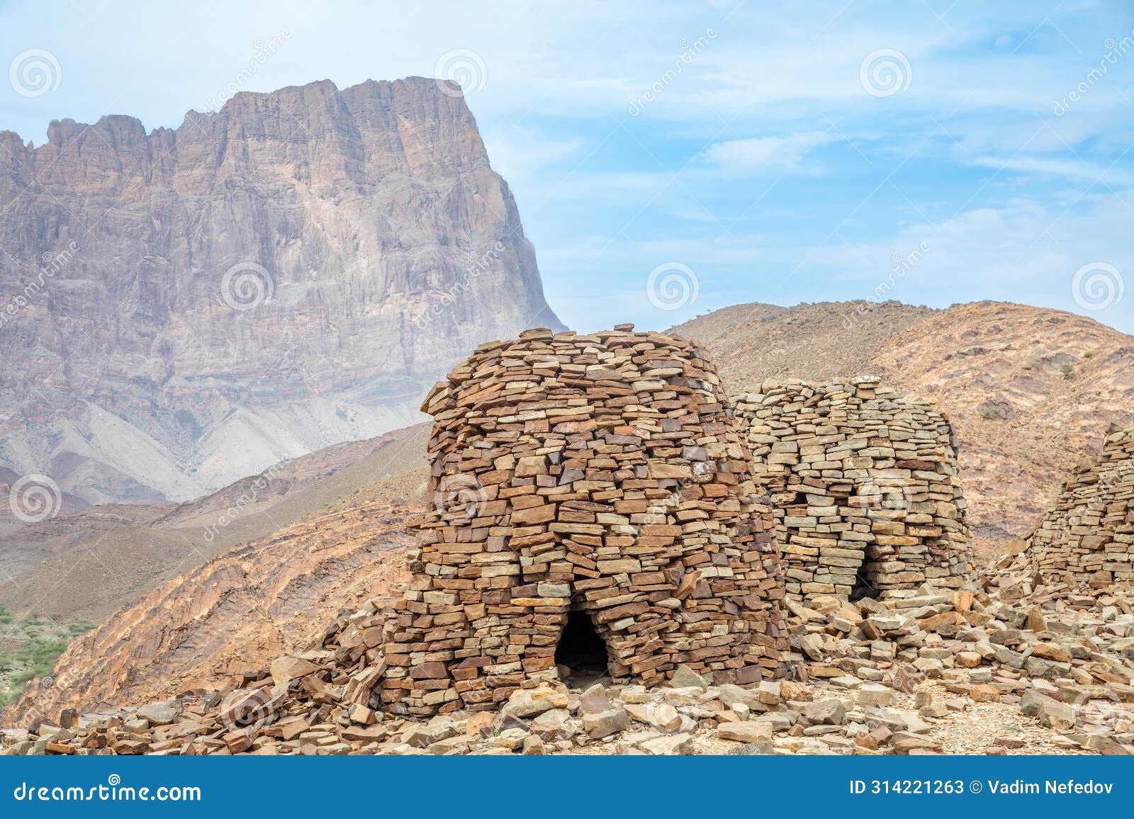 ancient stone beehive tombs with jebel misht mountain in the background, archaeological site near al-ayn, sultanate oman