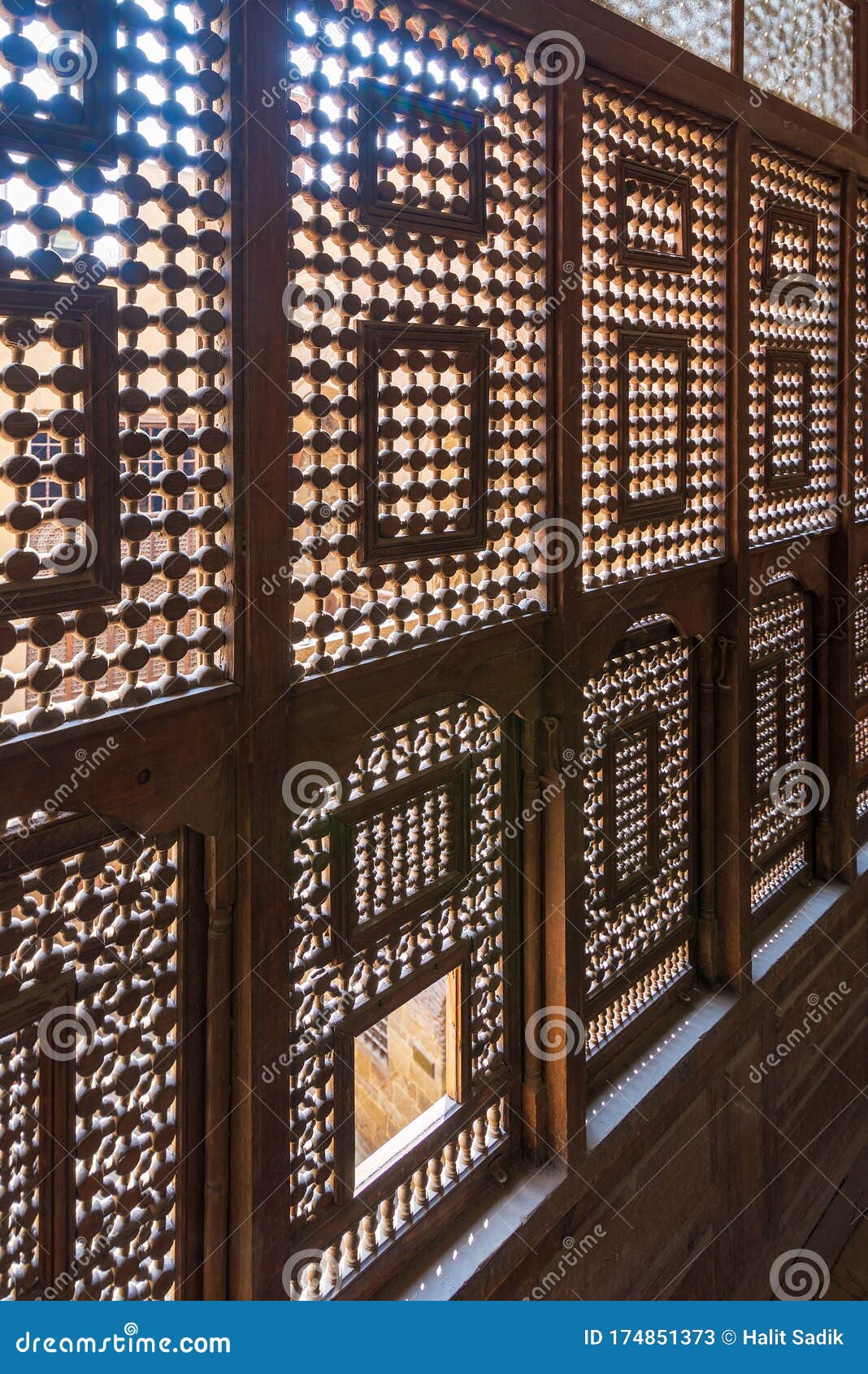 interleaved wooden ornate windows - mashrabiya - in stone wall at abandoned building
