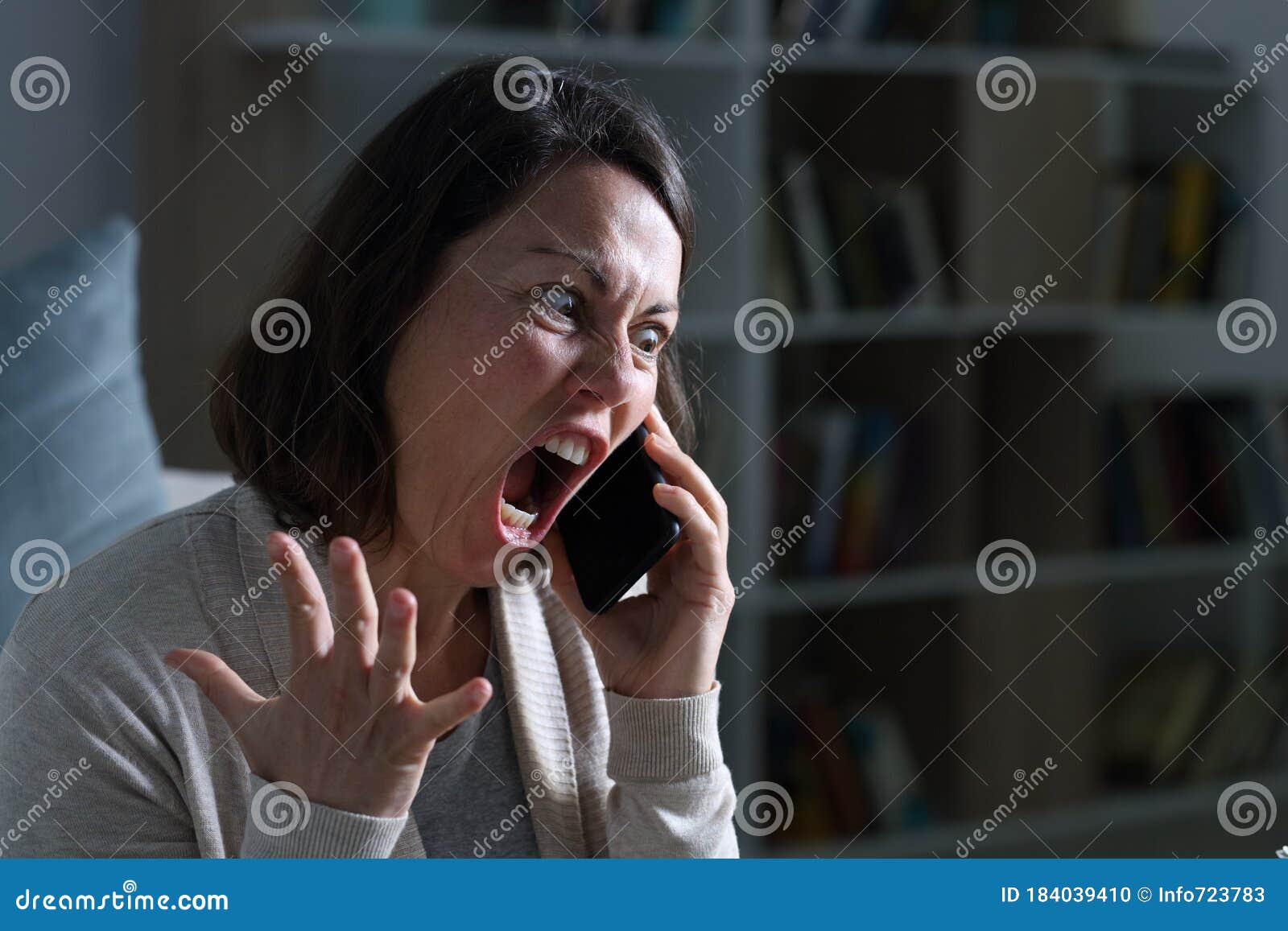 angry adult woman screaming calling on phone at night at home