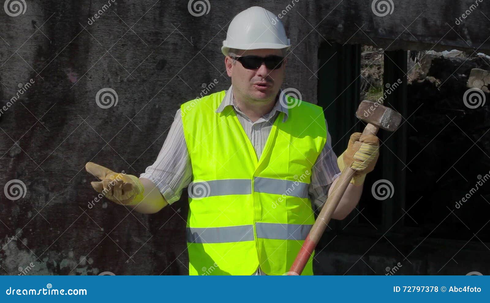 Angry Construction Worker with Sledgehammer Talking Near Wall Stock