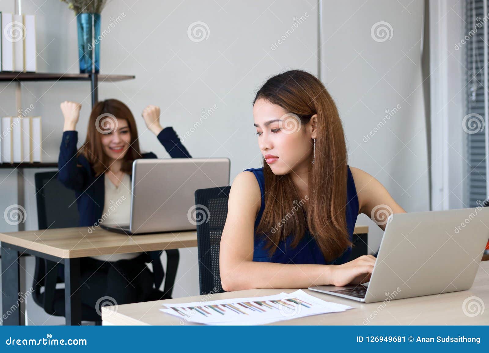 angry envious asian business woman looking successful competitor colleague in office.