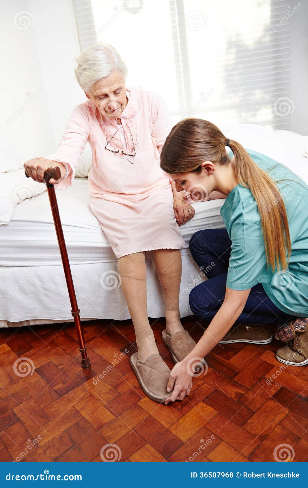Anhörigvårdaren hjälper att klä pensionären. Anhörigvårdarehjälp som hemma klär pensionärkvinnor på henne säng