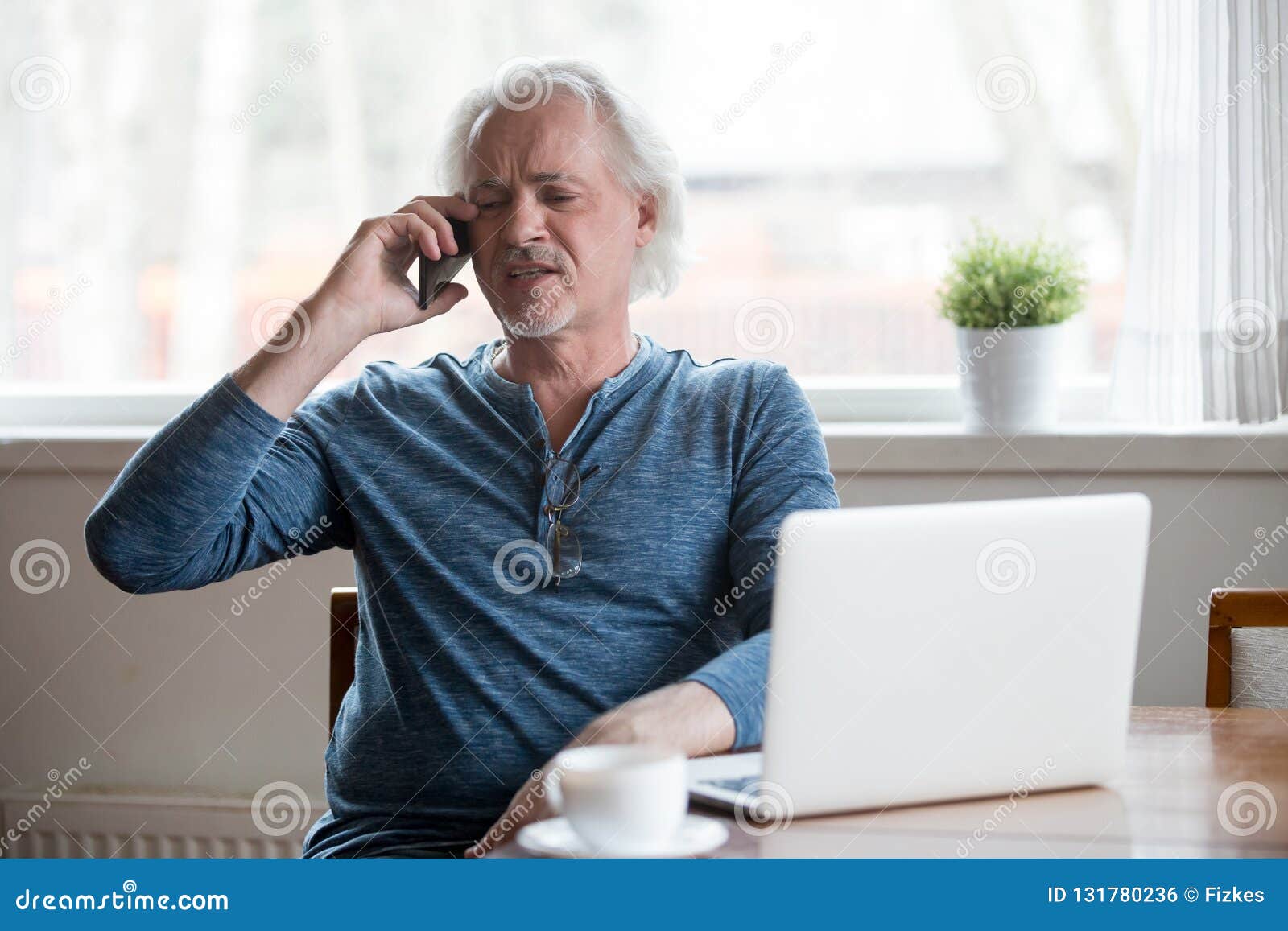 annoyed aged man having unpleasant phone talk