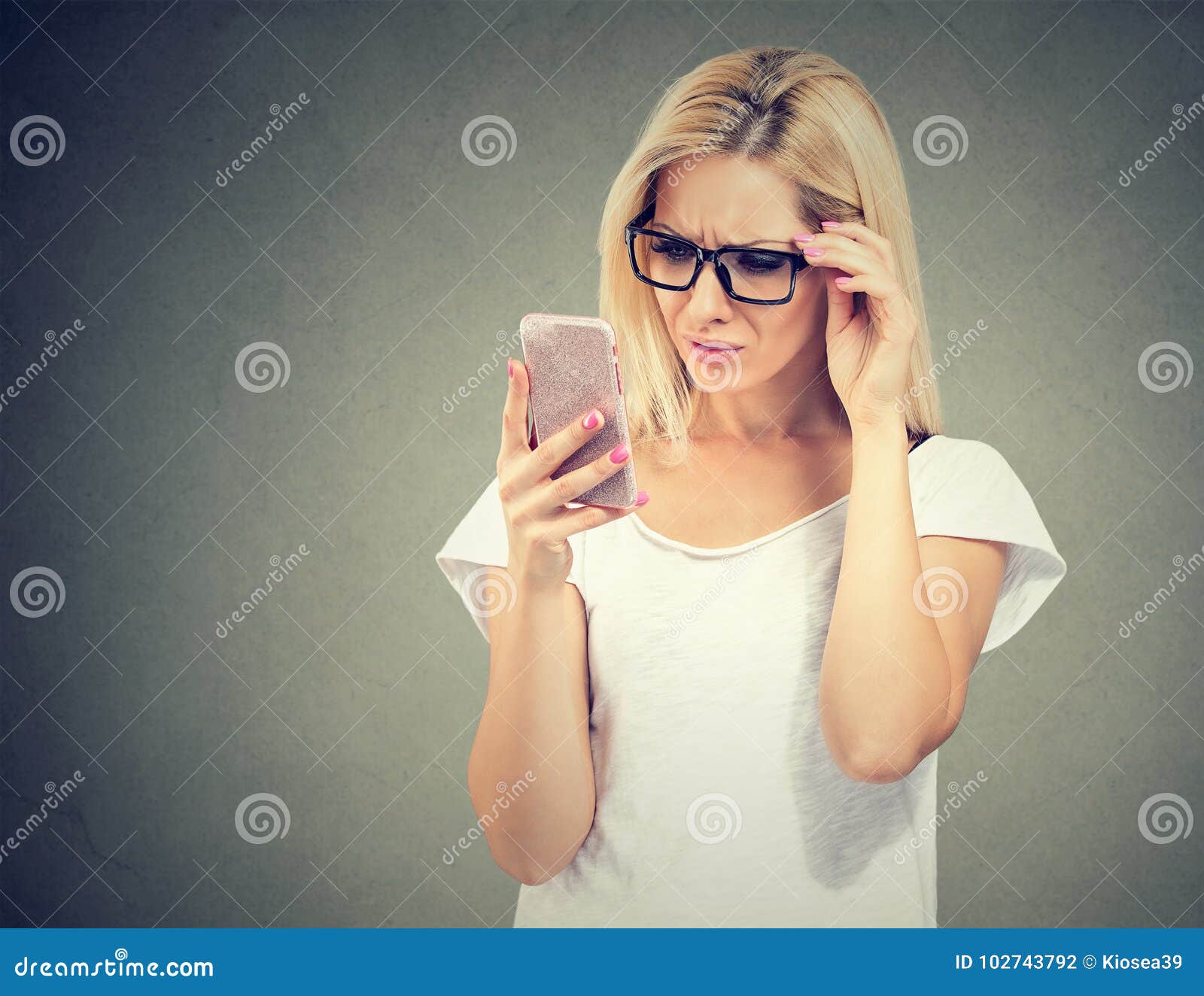 annoyed upset woman in glasses looking at her cell phone with frustration