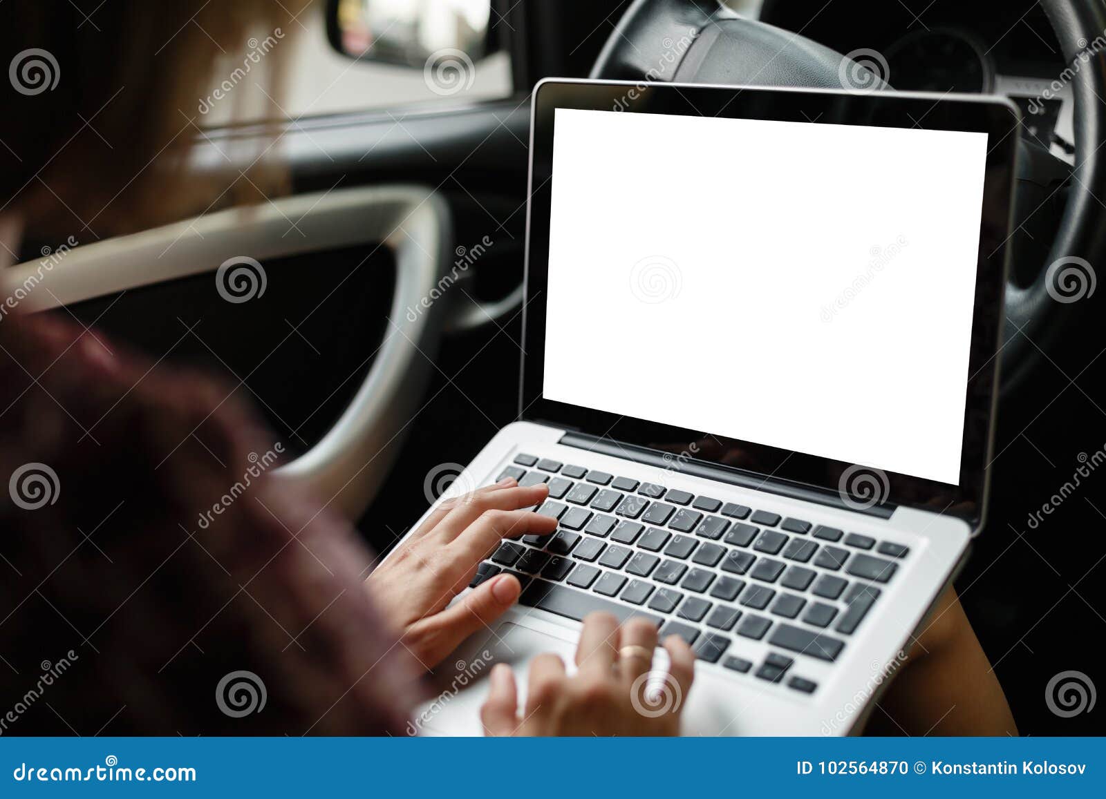 Anonymous woman browsing laptop in car. Crop mockup image of casual woman watching and using laptop while sitting on driver`s seat in car.