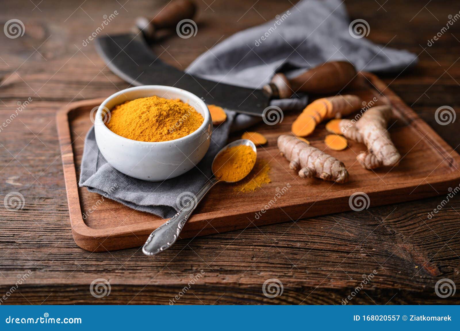 anti-inflammatory food ingredient, turmeric powder in a ceramic bowl and fresh root on wooden background