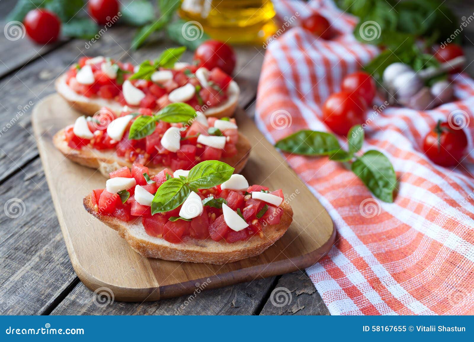 Antipasti italianos tradicionais caseiros do bruschetta com baguette, os tomates, manjericão e a mussarela roasted no fundo de madeira do vintage Estilo rústico e luz natural