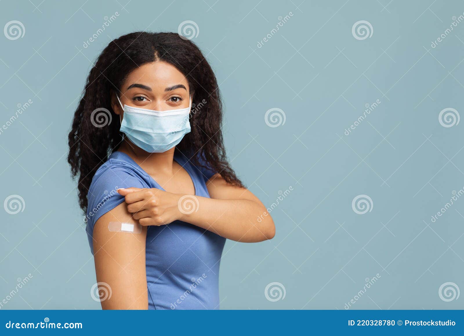 antiviral immunization. black lady vaccinated against covid-19, showing arm with plaster, standing on blue background