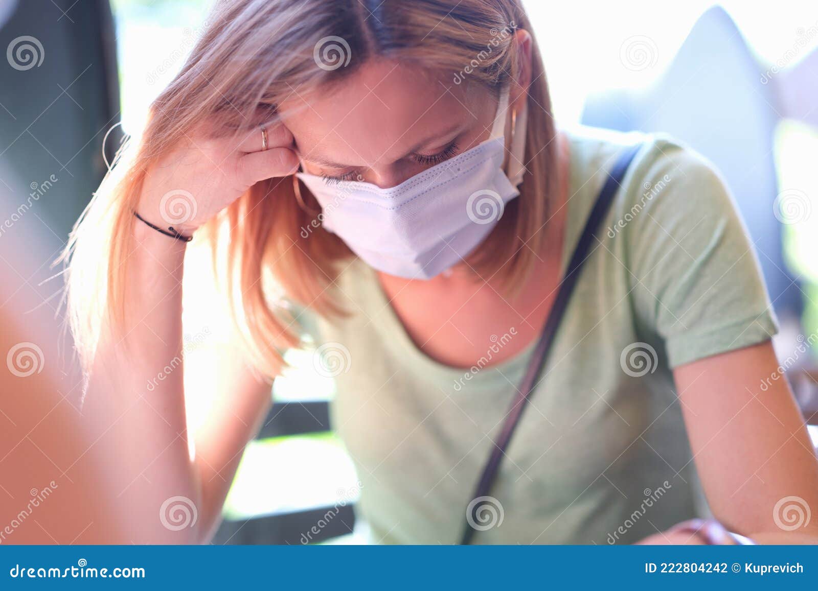 anxious sad woman in medical protective mask sits at table