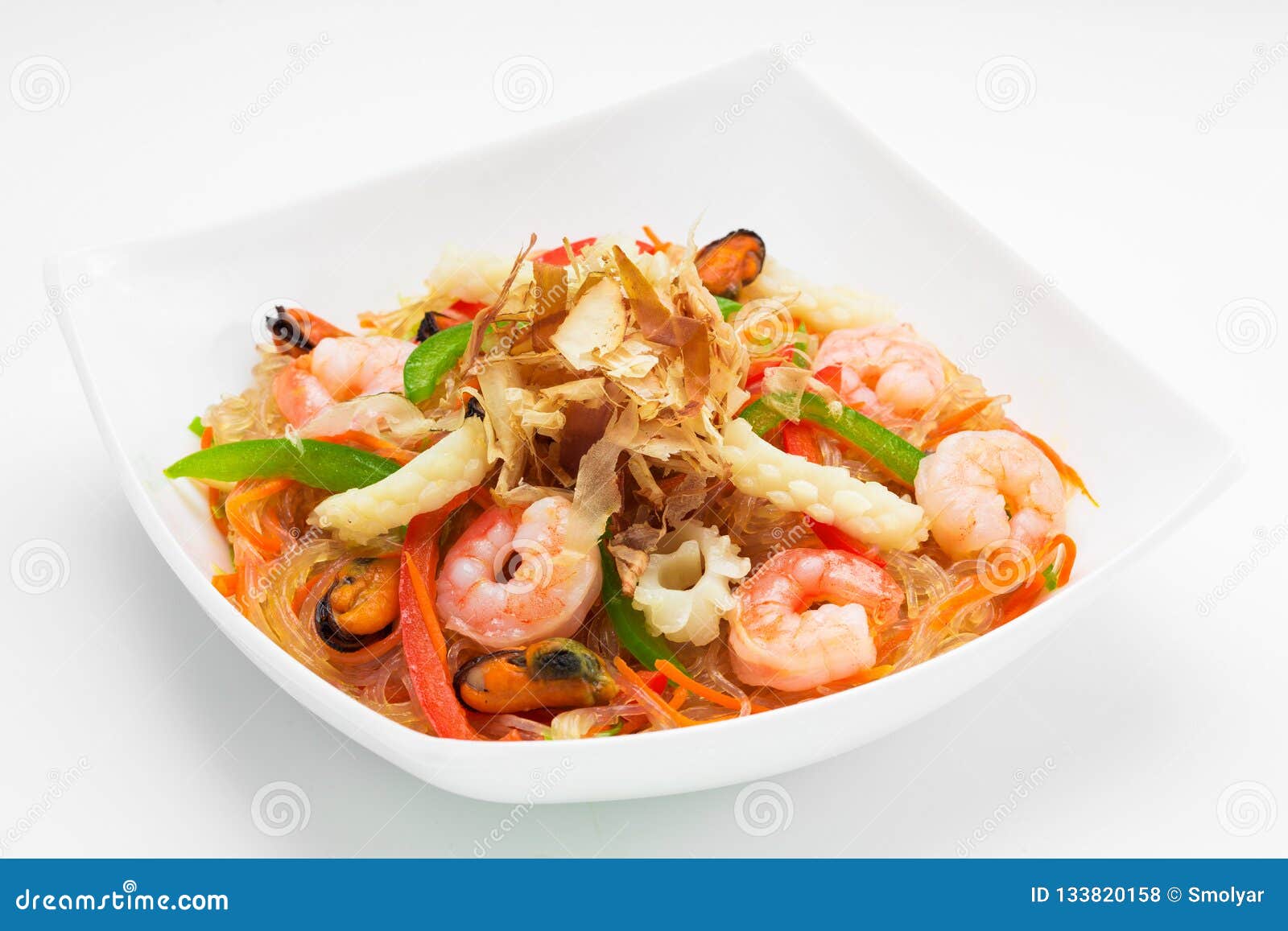 appetising cellophane noodles with seafood in a white plate, close up on a white background