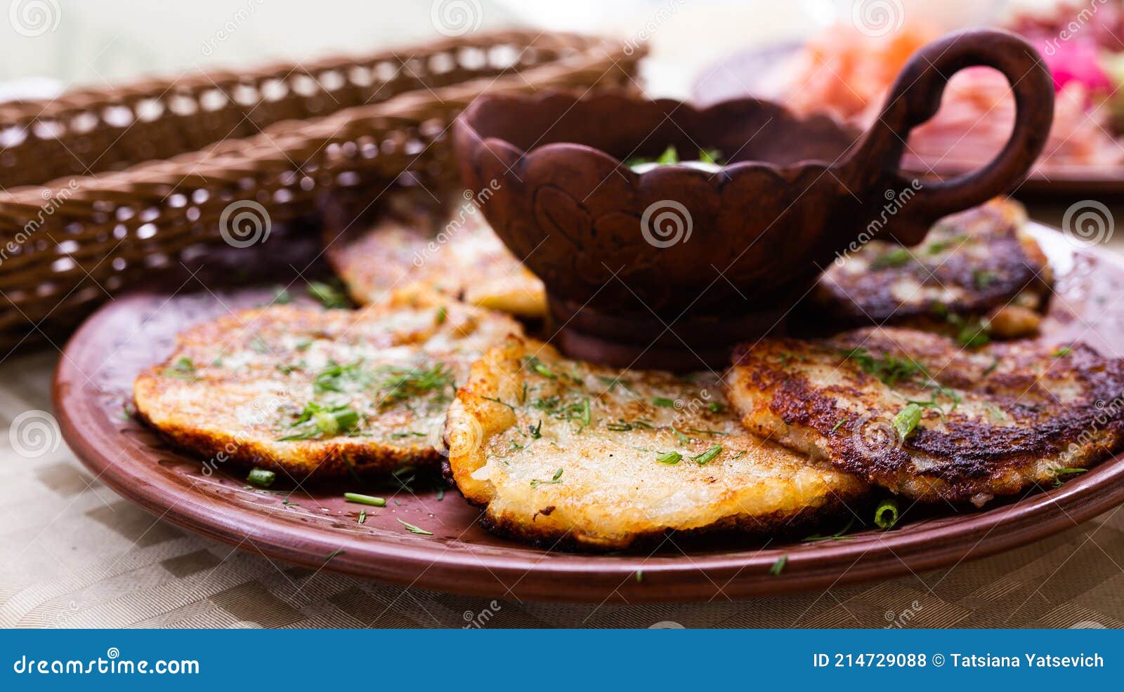 potato pancakes with sour cream and herbs on white plate