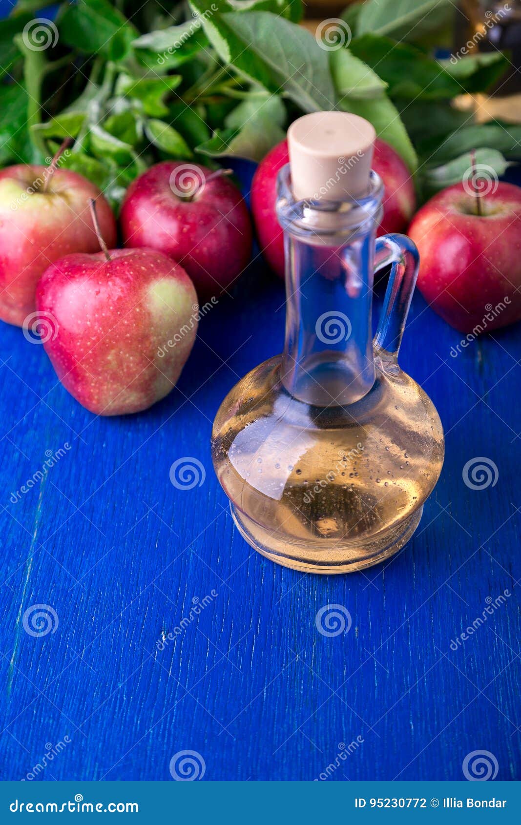 Apple Cider Vinegar. One Glass Bottle on Blue Background. Red Apples