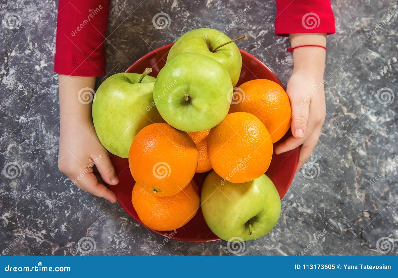 Apples and Oranges in the Hands of a Child. Stock Image Image of