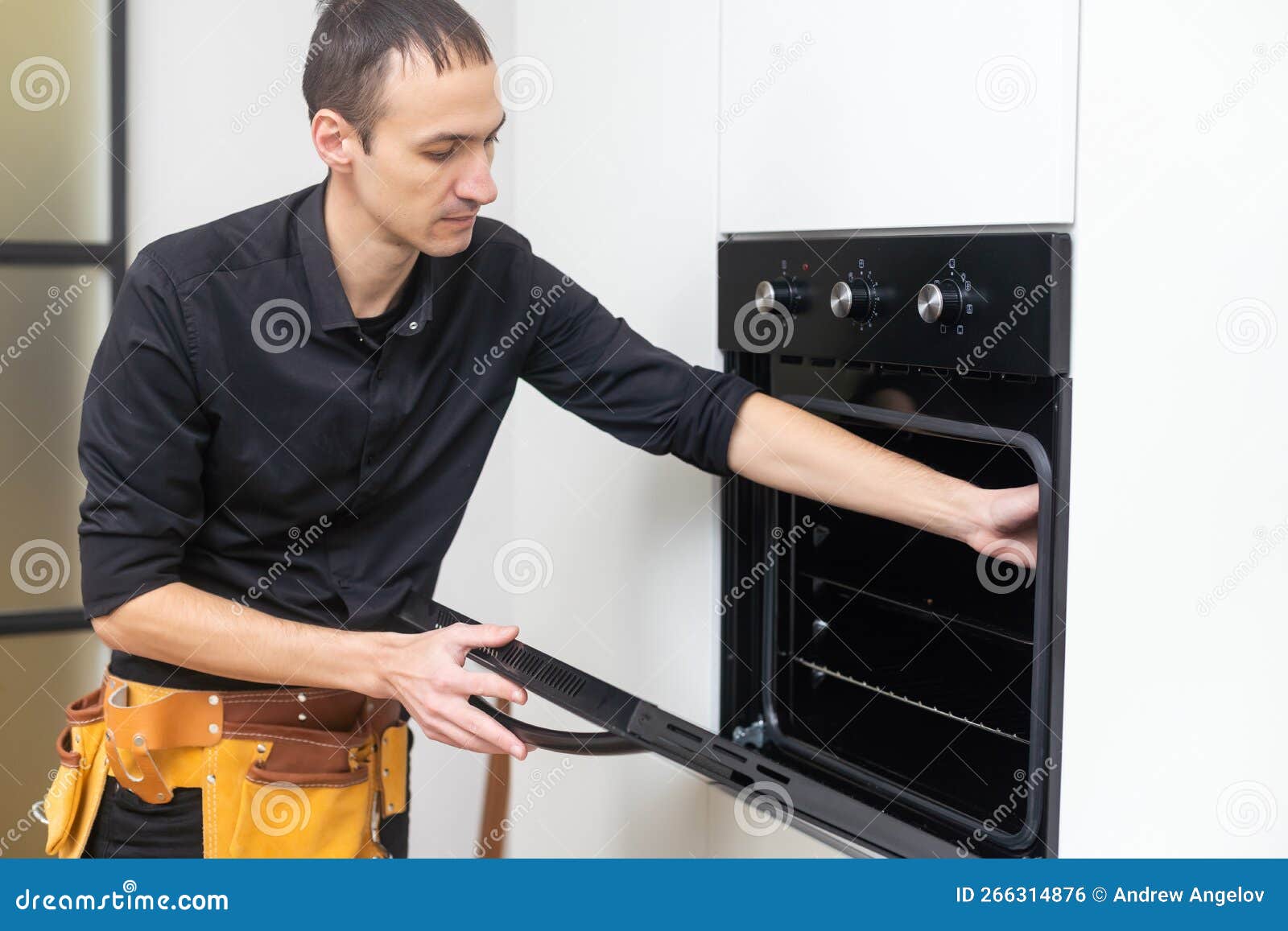 Appliance Repair. Man Installing Electricity Oven in the Kitchen Stock