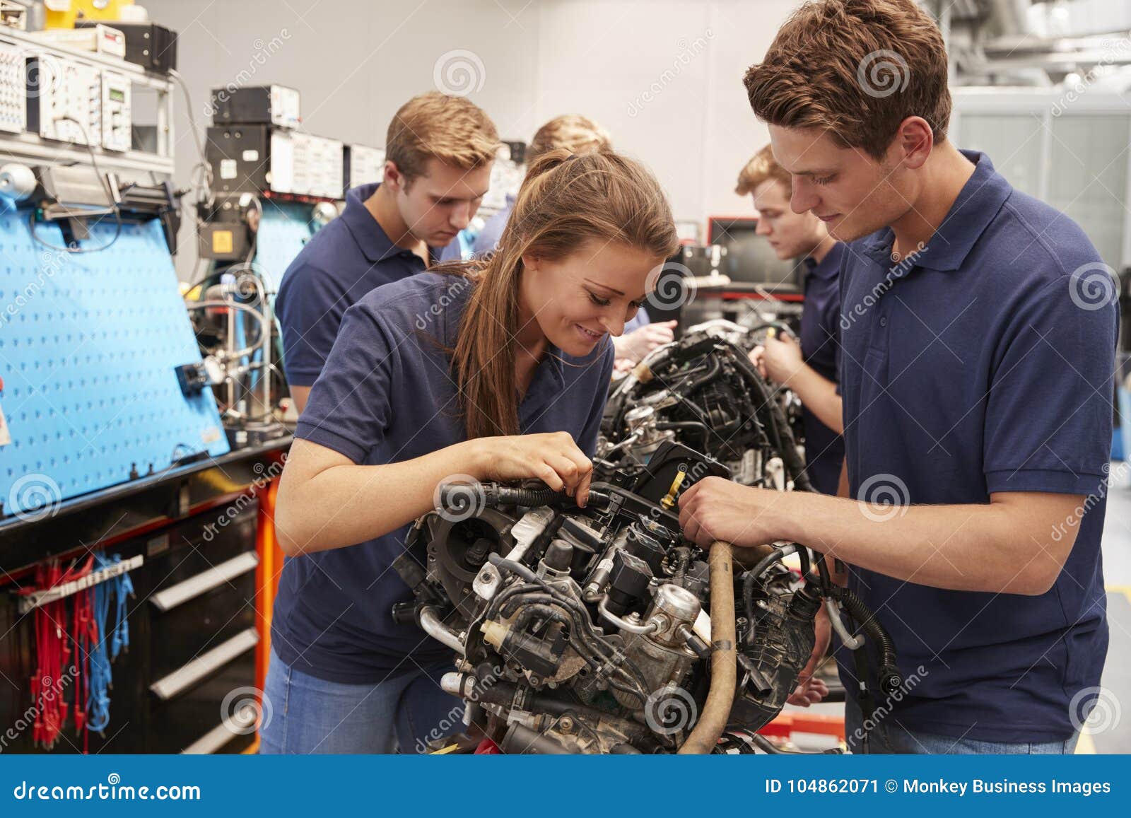 apprentice car mechanics working on an engine