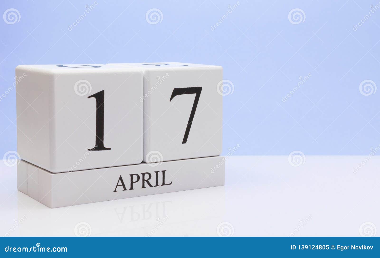 april 17st. day 17 of month, daily calendar on white table with reflection, with light blue background. spring time, empty space