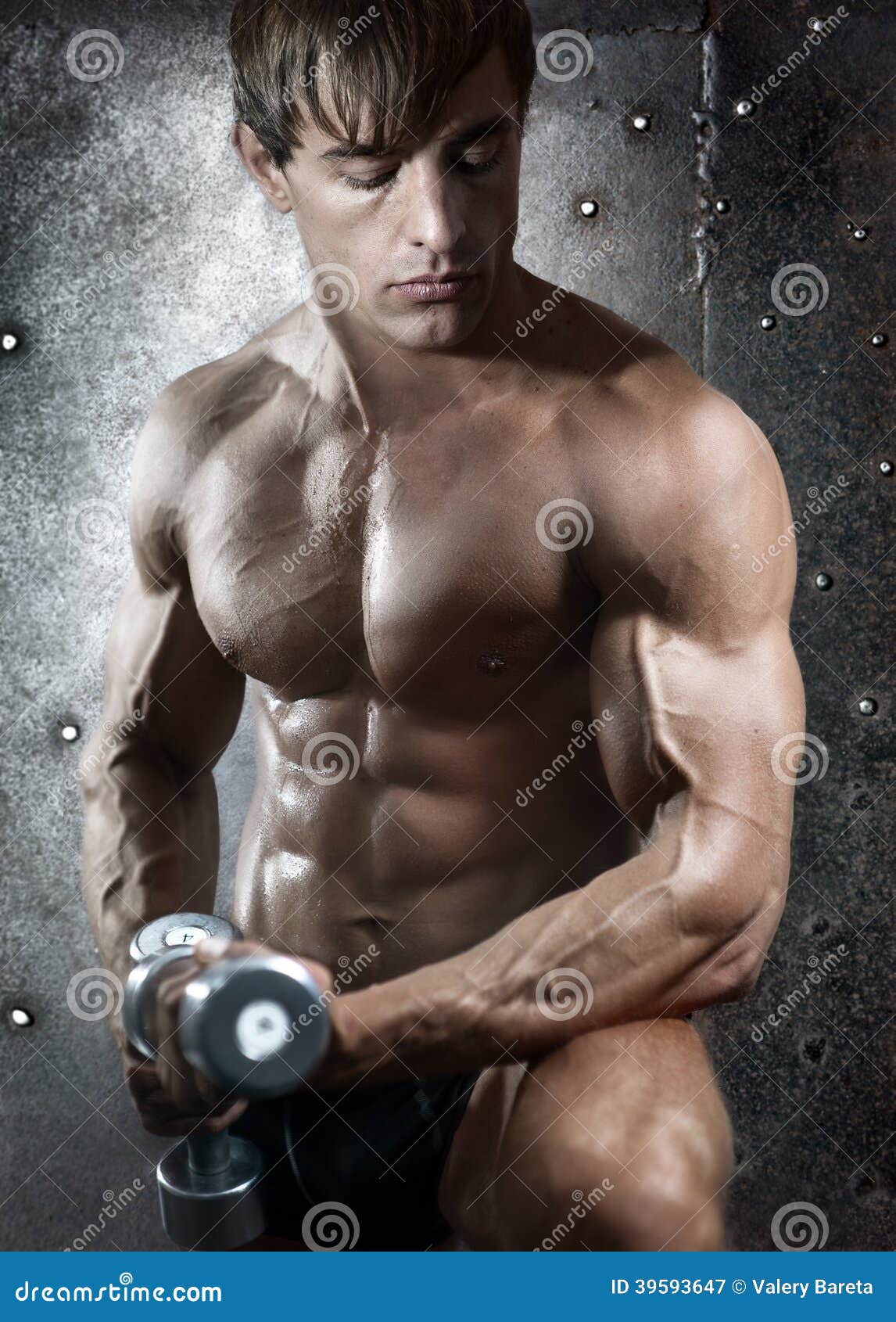 Aptitud. Retrato con el torso atlético desnudo del hombre hermoso joven con pesas de gimnasia